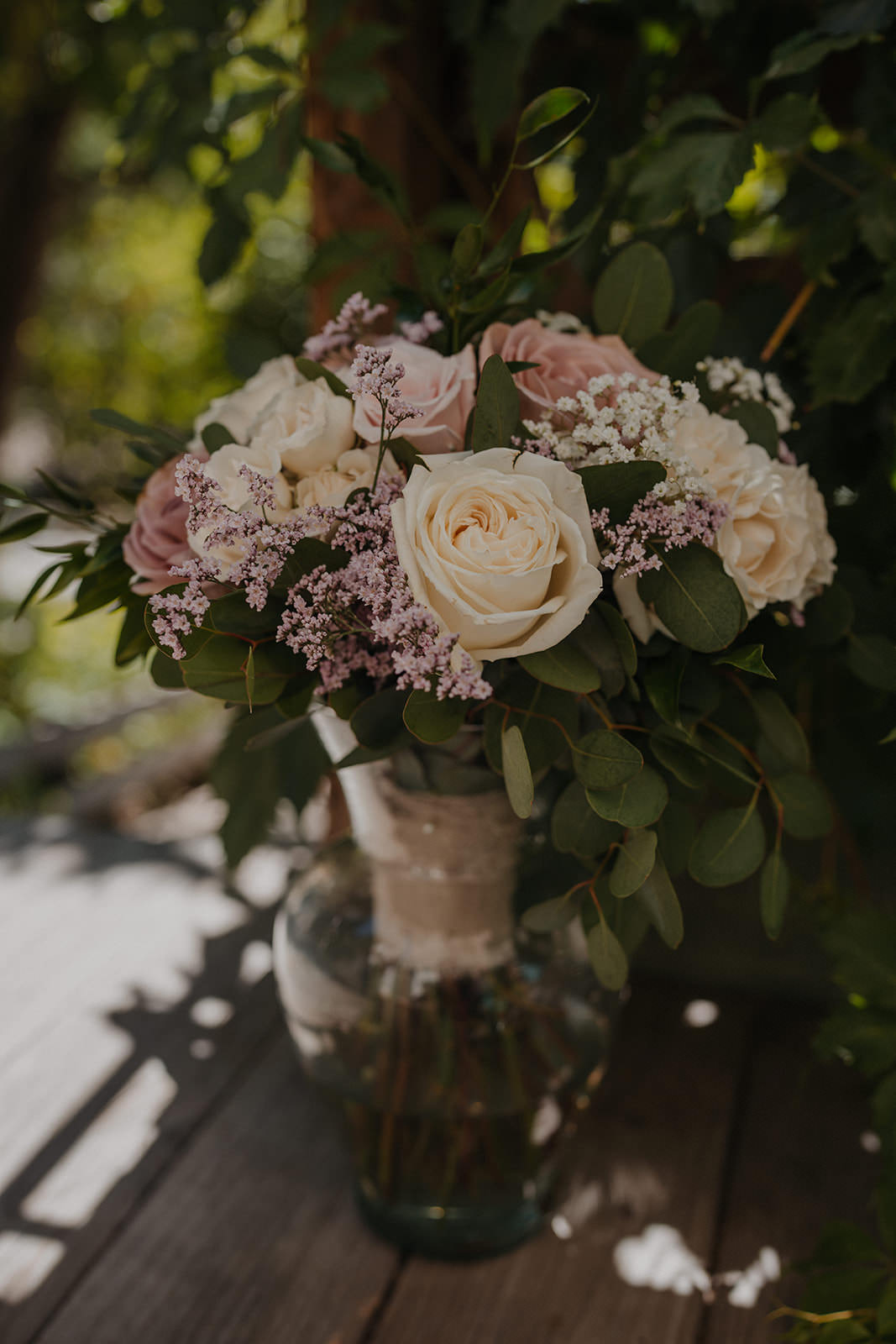 Bride's bouquet of white roses and eucalyptus at an outdoor wedding.