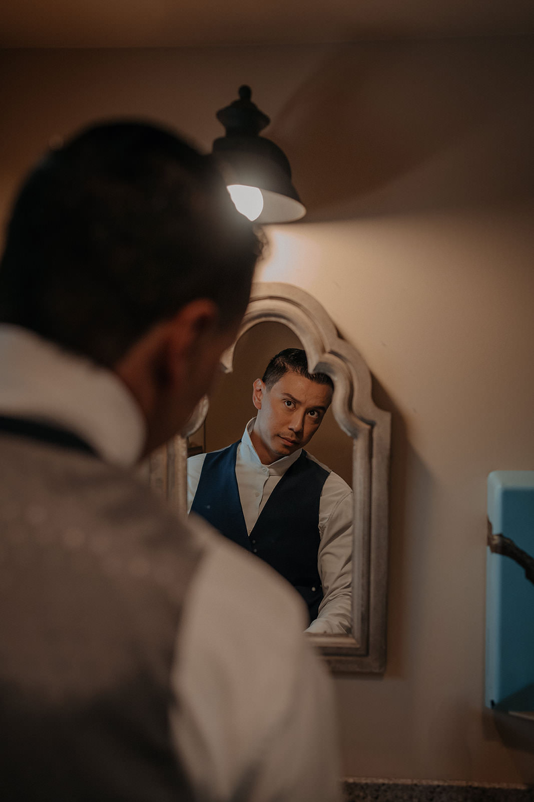 Groom getting ready in the mirror in the grooms cabin at the homestead in oak glen