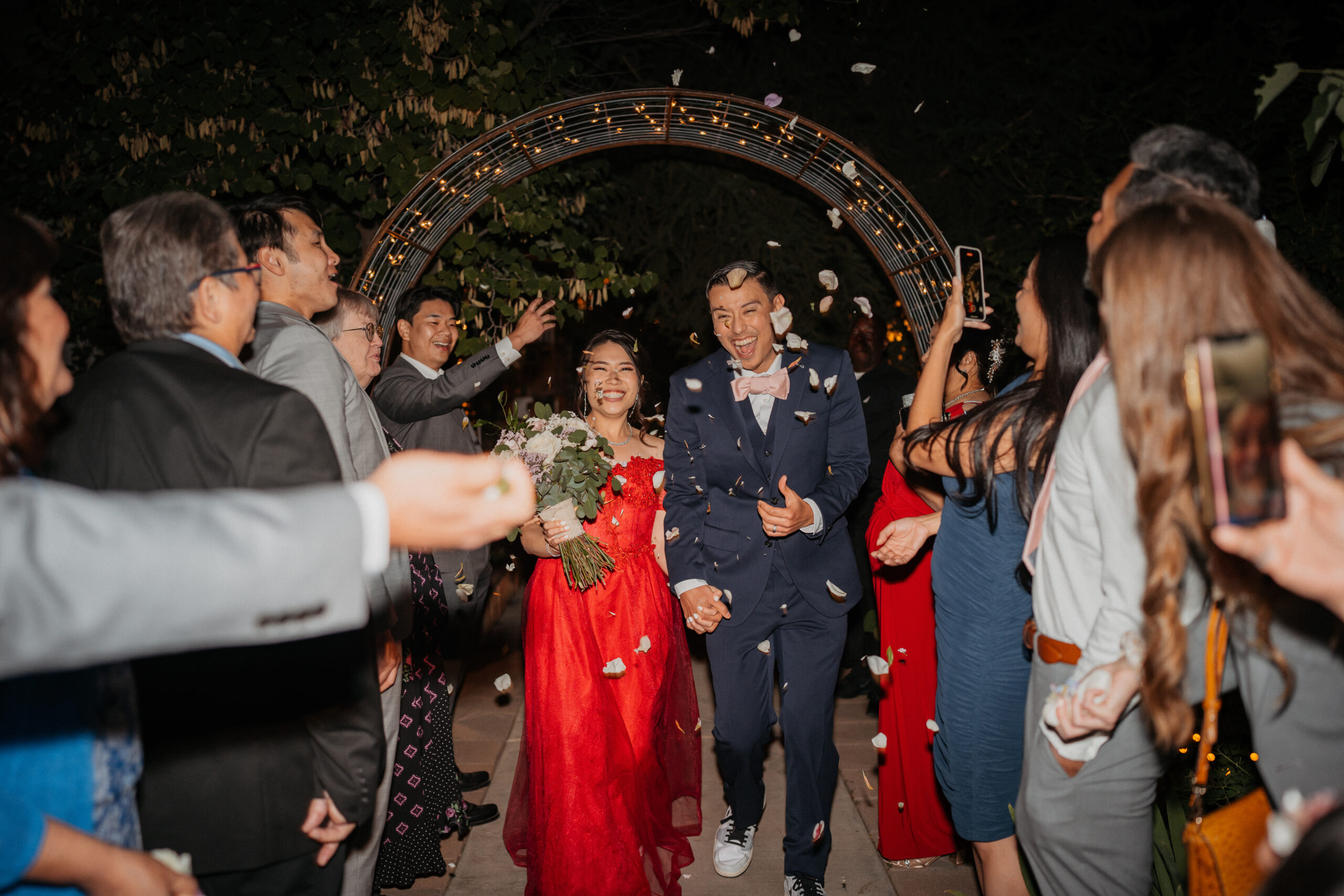 Bride and groom exit their reception with guest throwing flower petals around them.