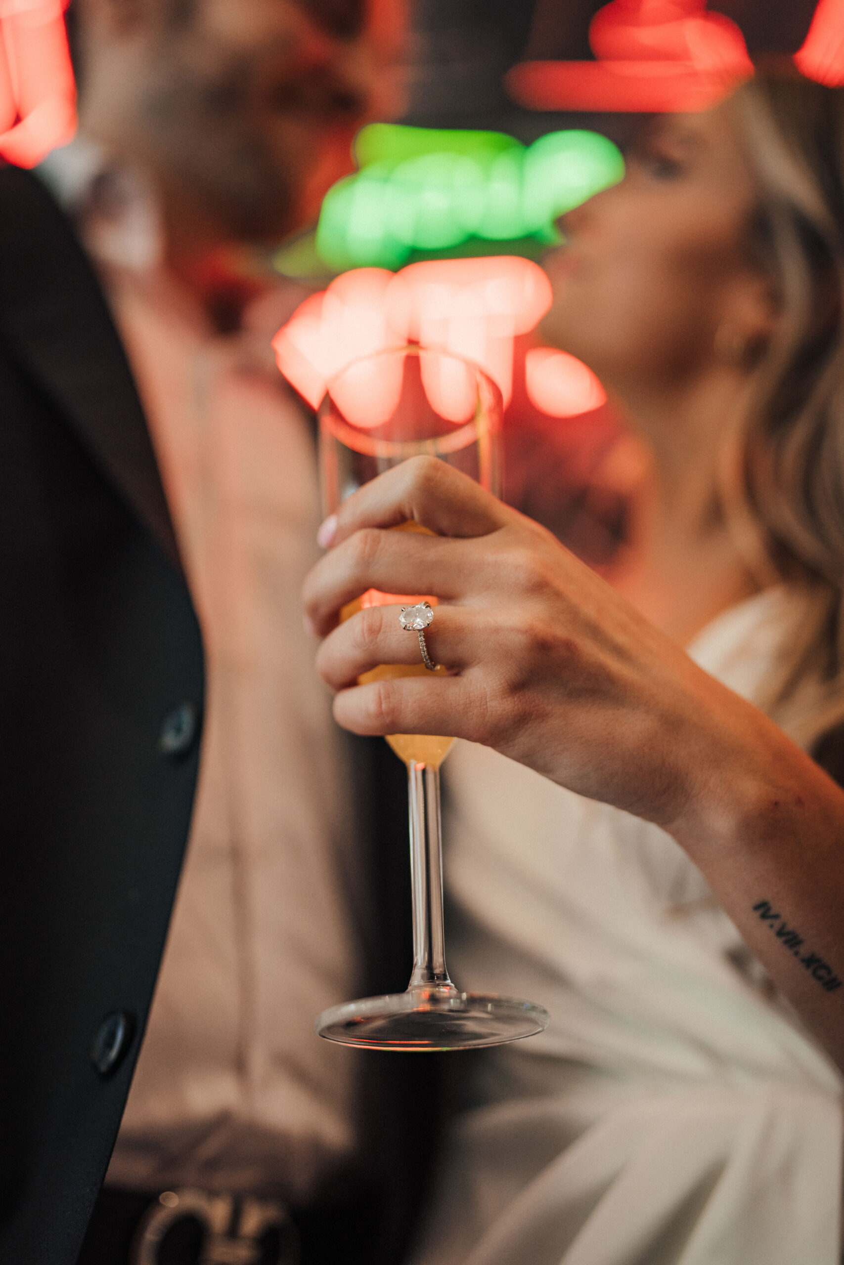 Engagement ring shot with champagne glass in front of neon signs at Grand Central Market LA
