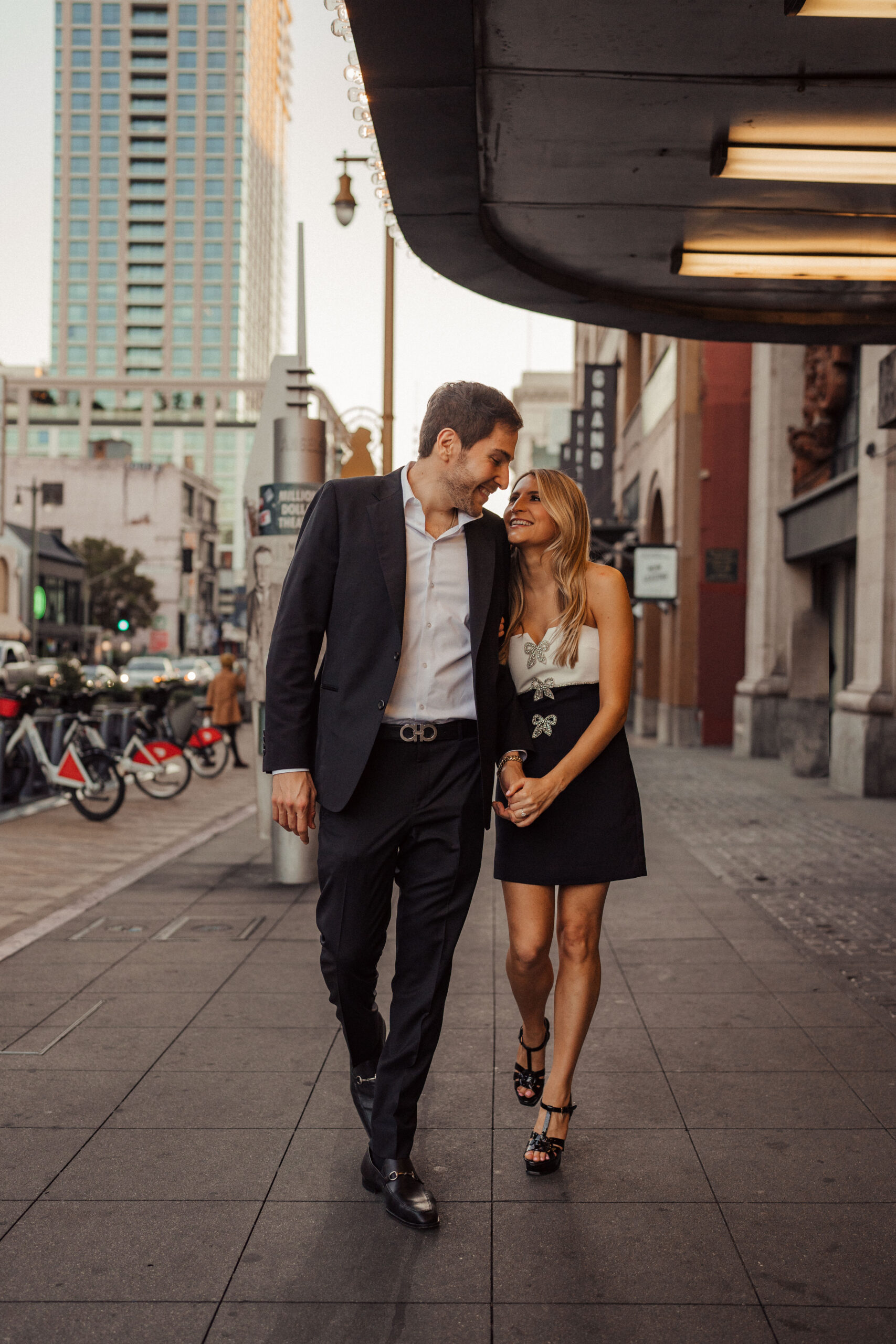 Engaged couple walks through Downtown LA together at Grand Central Market for engagement photos 
