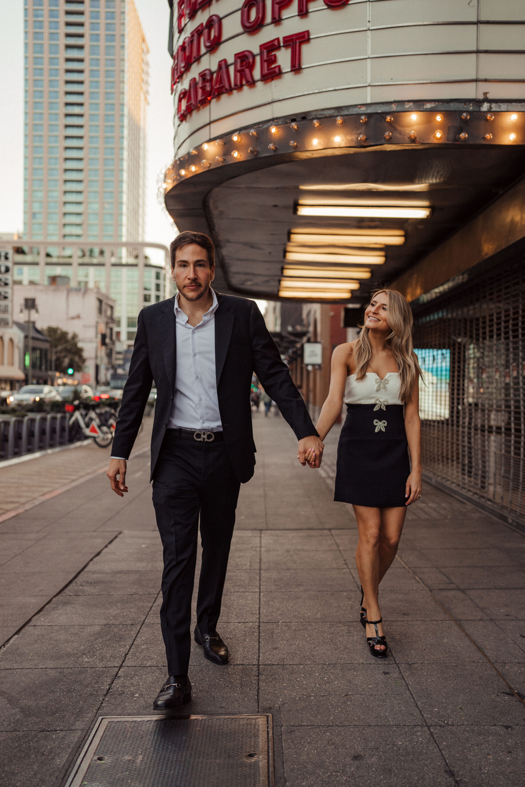 Engaged couple walks through Downtown LA together at Grand Central Market for engagement photos 