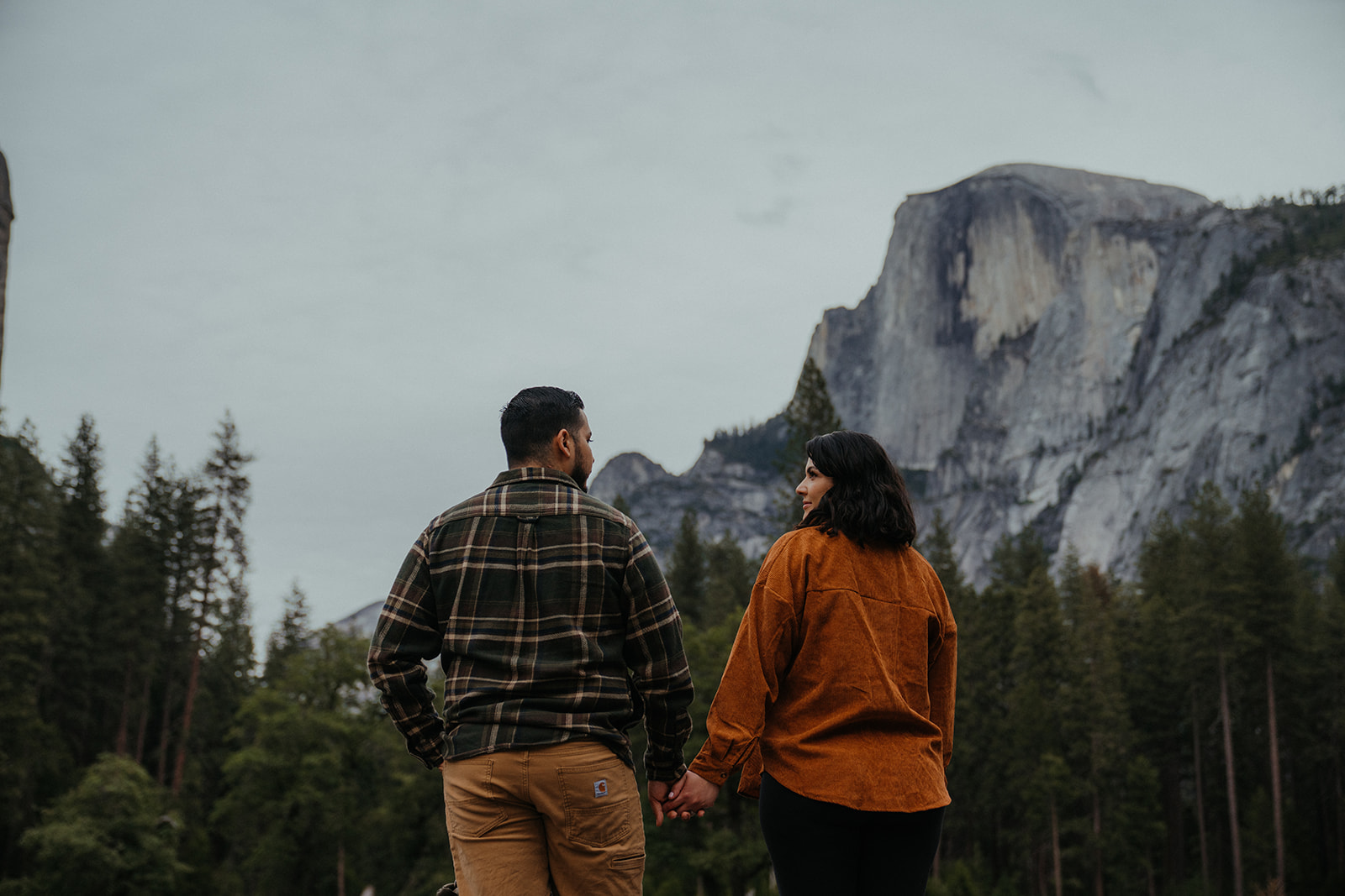 Couple holds hands with each other with the view of Yosemite valley in the background
