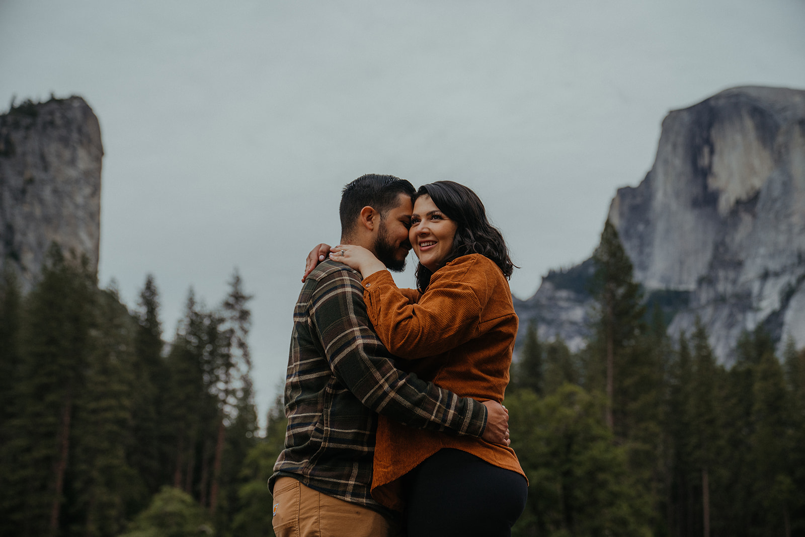 Couple hugs each other with the view of Yosemite valley in the background