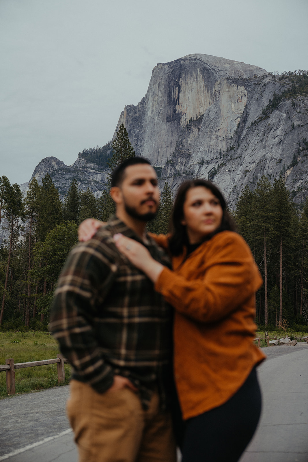 Adventurous couple hugs each other with the view of Yosemite valley in the background